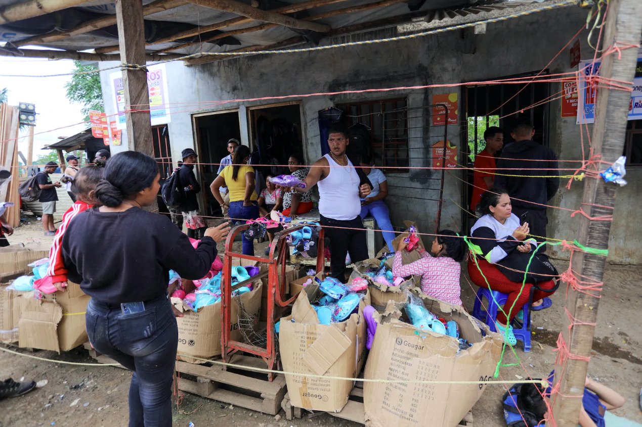 2023年9月23日，巴拿馬達(dá)連省拉哈斯布蘭卡斯移民接待站等待前往美國的移民，一名男子將捐贈(zèng)的鞋子遞給一名懷著嬰兒的婦女。