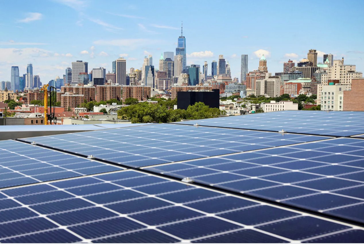 2022年8月16日，在美國(guó)紐約布魯克林公園坡社區(qū)，從該市第一座大型木結(jié)構(gòu)公寓樓TimberHouse的屋頂上可以看到太陽(yáng)能電池板以及附近地區(qū)和曼哈頓下城的景色。