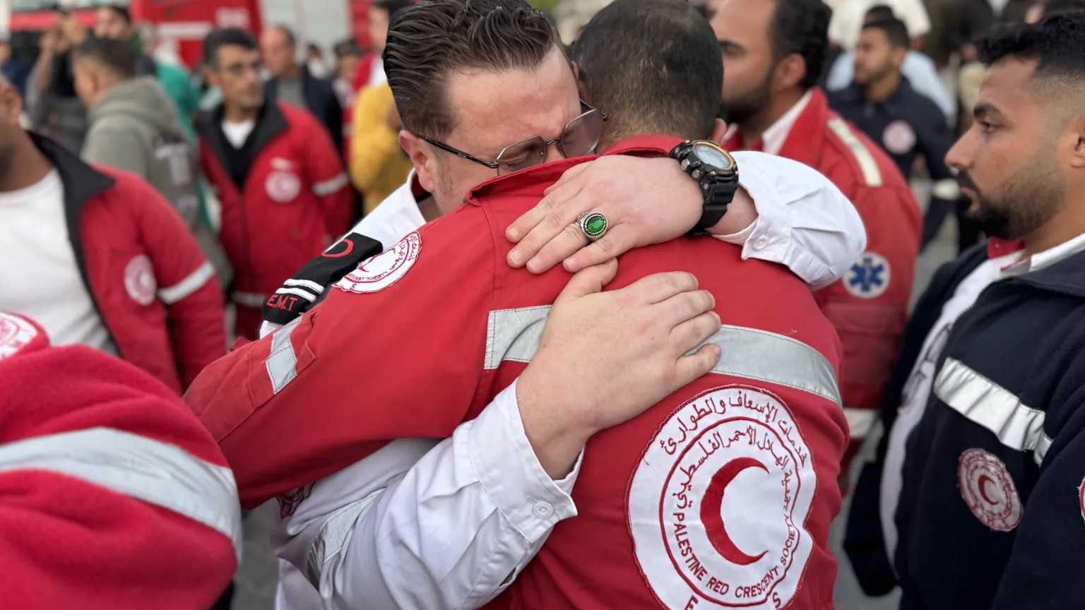 巴勒斯坦紅新月會(huì)的員工們擁抱在一起，看著同事的遺體被送往加沙南部汗尤尼斯的一家醫(yī)療機(jī)構(gòu)